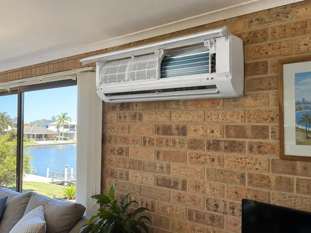 Clean split system on a brick wall above a lounge with open front panel and visible filters in Broadbeach Waters