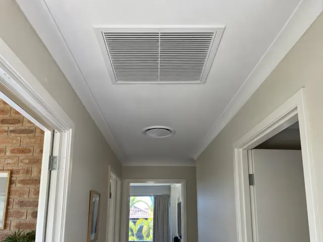 Hallway ceiling with a flush return-air grille and round ceiling fitting in a home interior in Mermaid Waters